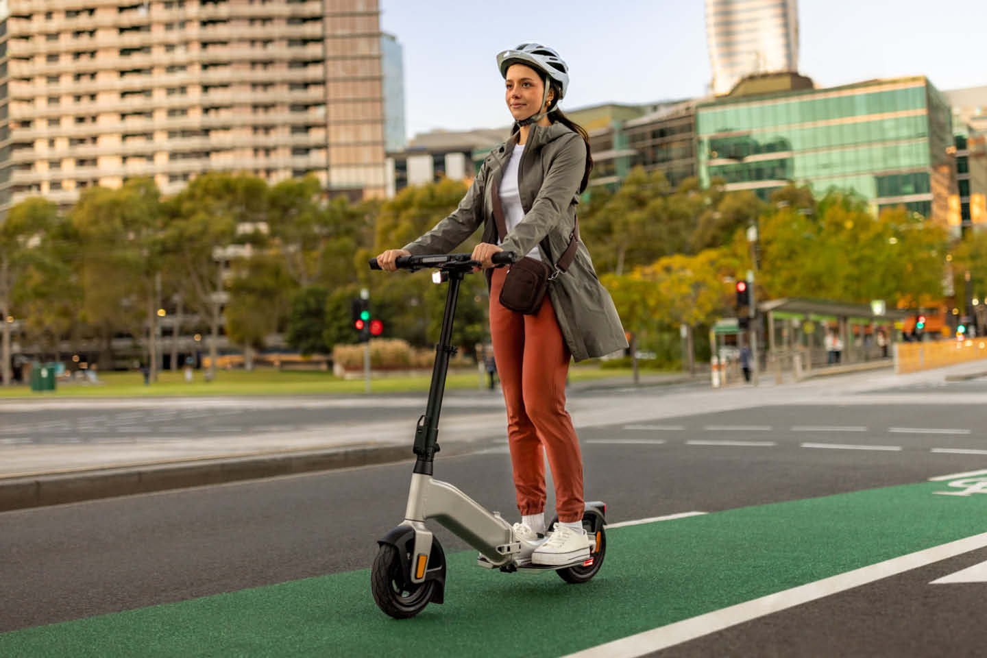 Photograph of a woman wearing a helment and riding an e-scooter in a Melbourne bike lane