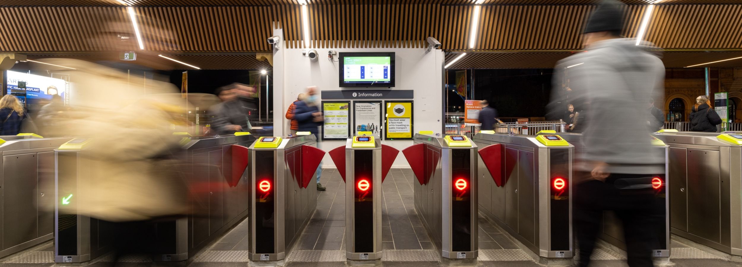 People walking towards and away from ticket barriers at a train station