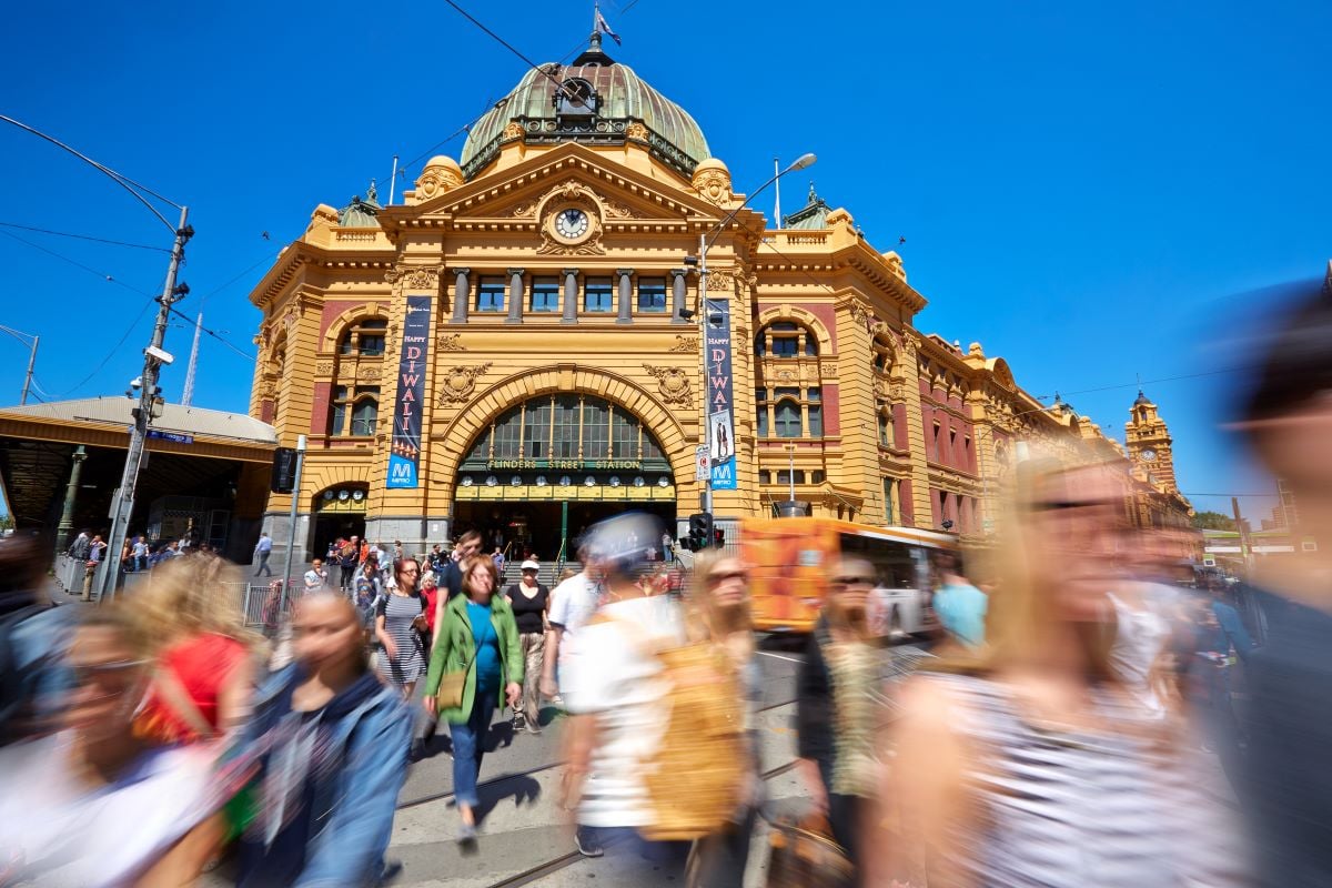 People walking in front of Flinders Street station on a sunny day