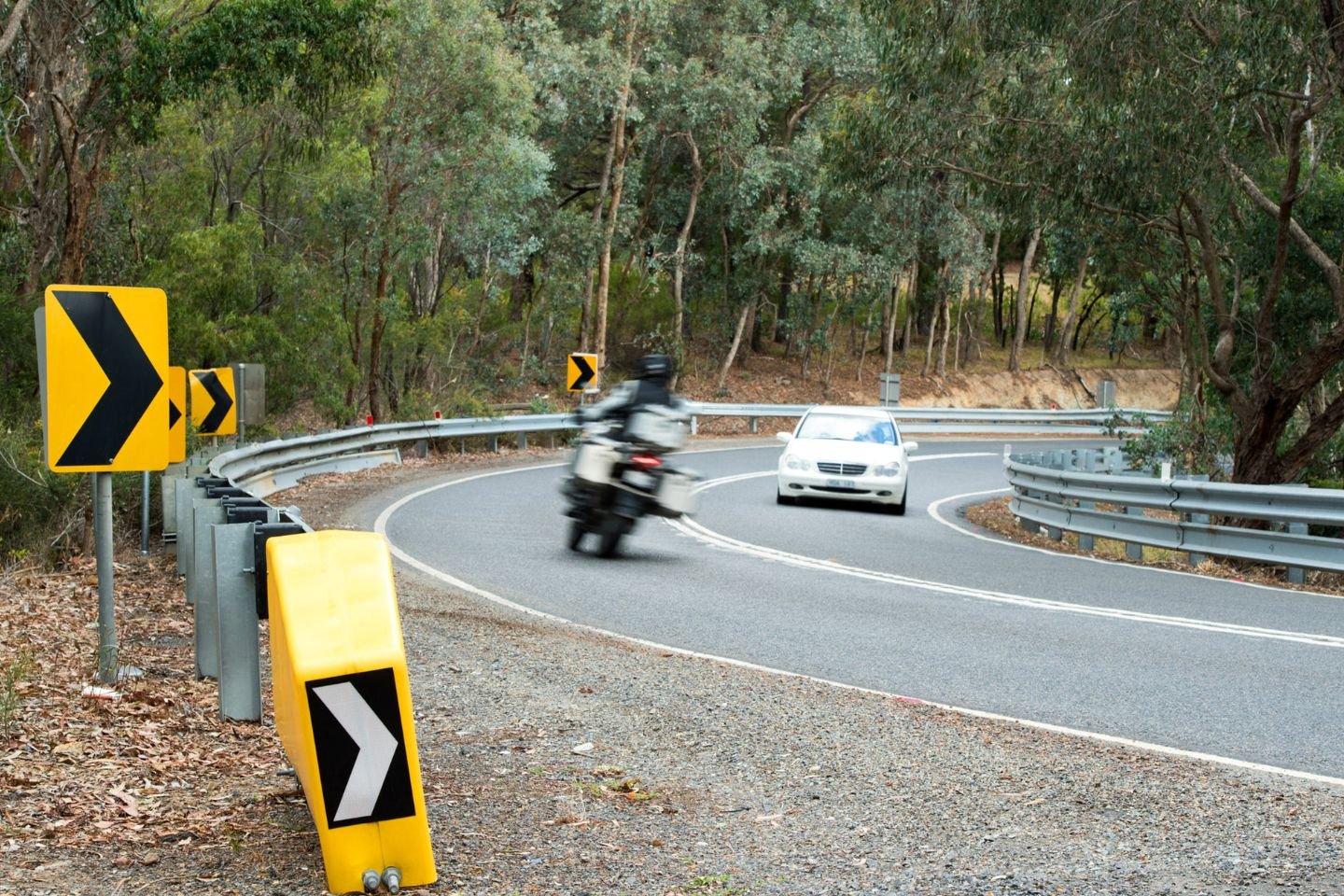 A car and motorbike passing each other on a regional road.
