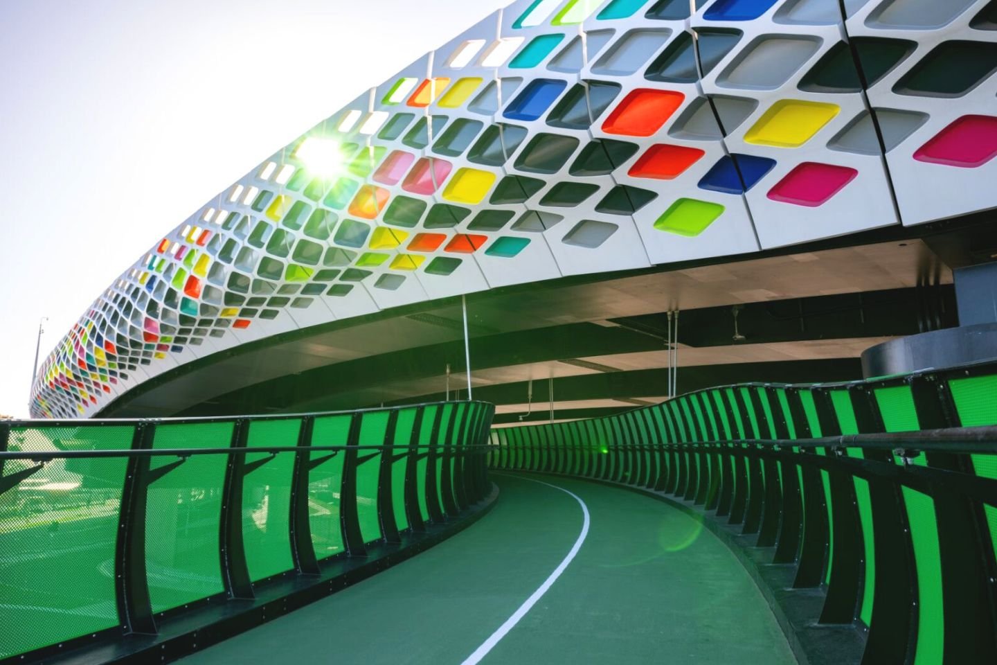 The new Footscray veloway. It has a green surface with green transparent panels on the side. It's topped by a rainbow coloured vehicle overpass.