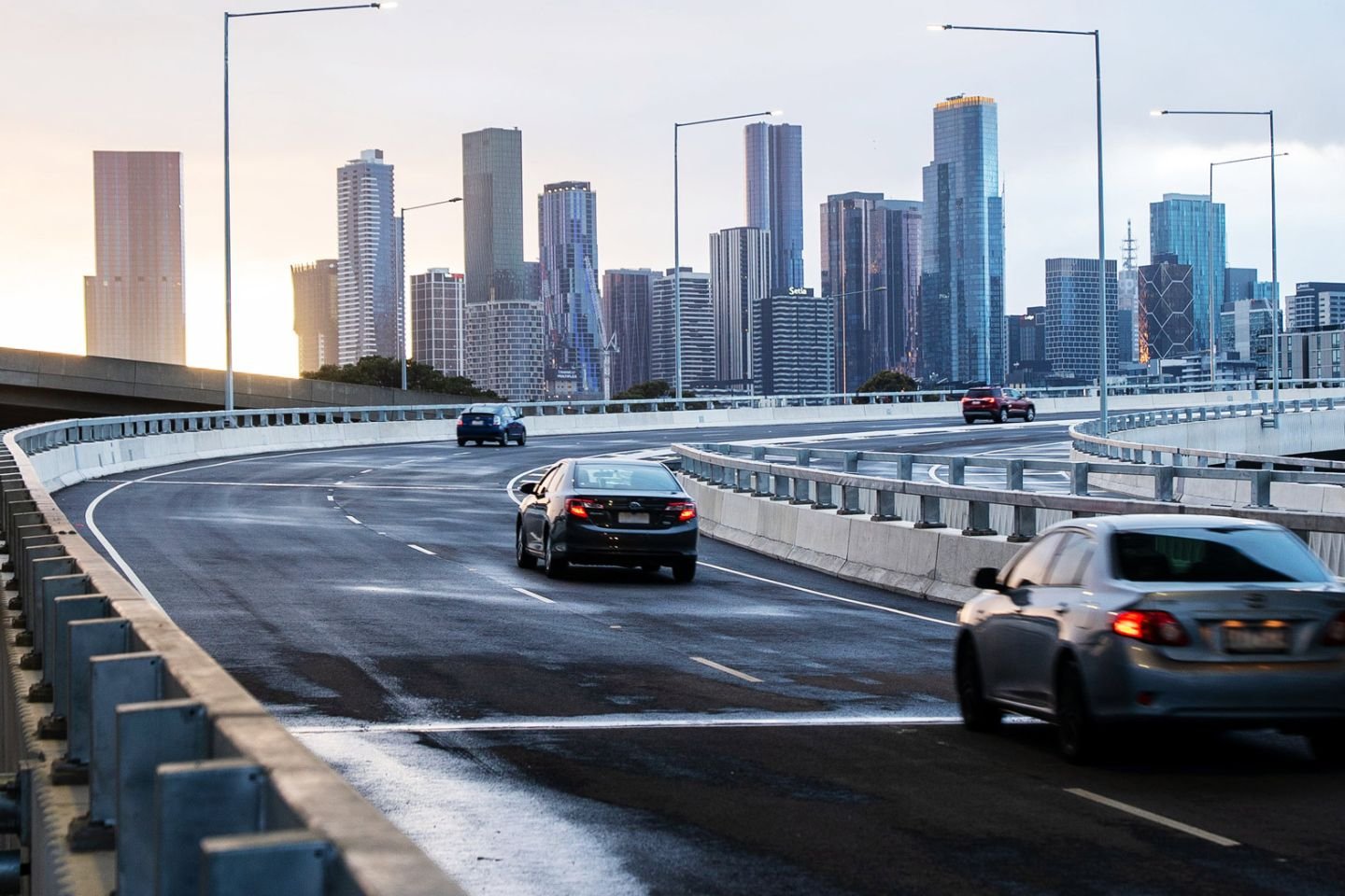 Cars driving over a bridge at sunset.
