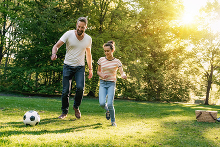 Dad and daughter playing soccer at a park