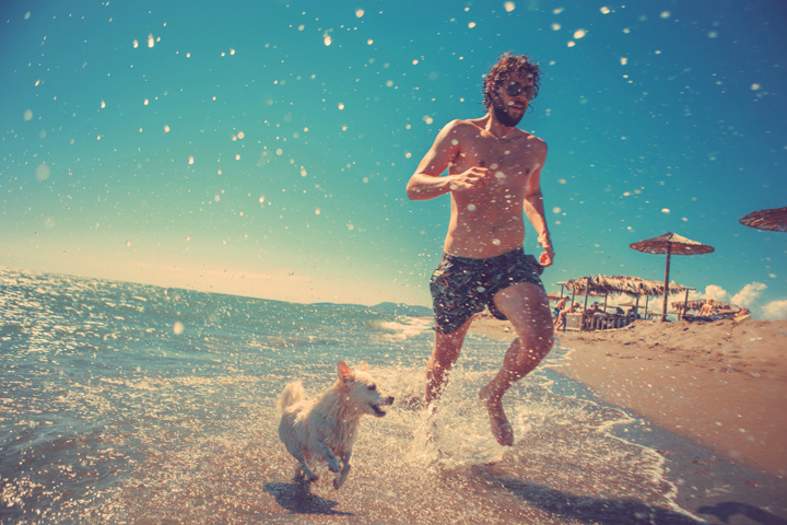 dude and his dog run on beach