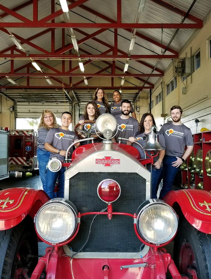 Suncoast Credit Union staff by a vintage firetruck in a firehouse in Plant City