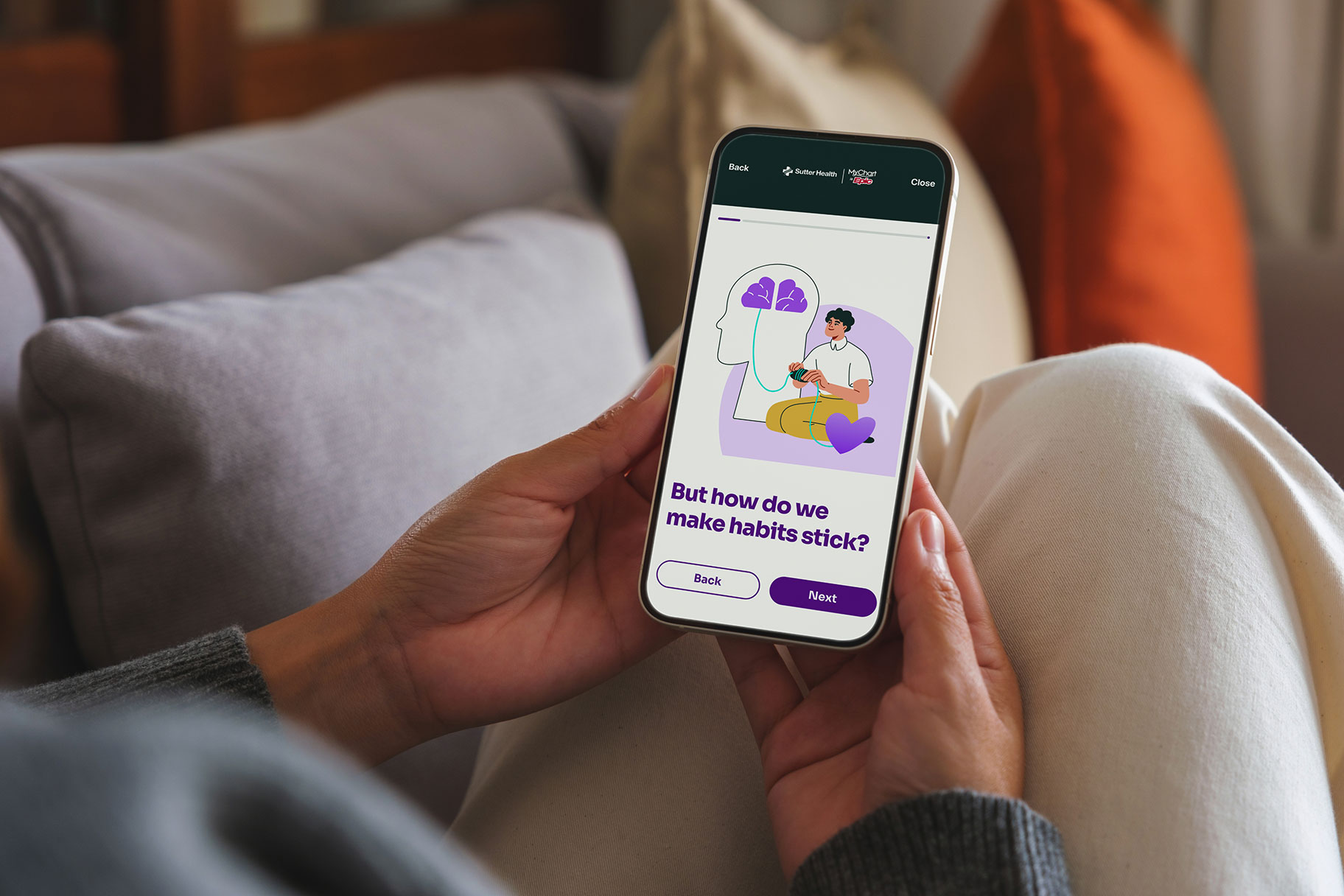 Woman on couch viewing health guides on her cell phone.