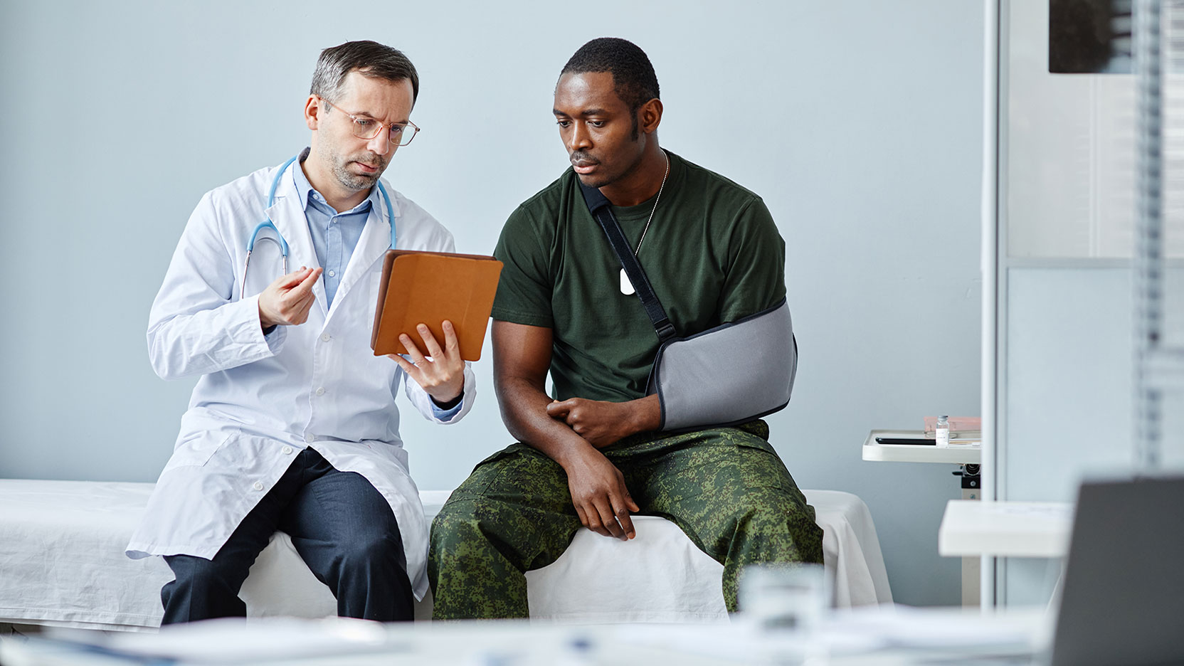 Man in sling speaking to an orthopedic doctor