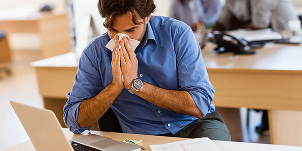 Man sneezing at work