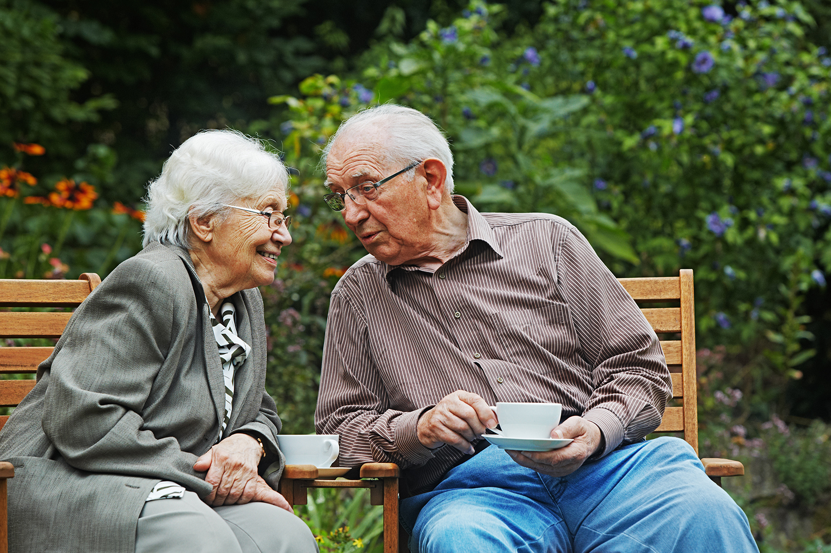 Elderly couple enjoying coffee while sitting outside. 