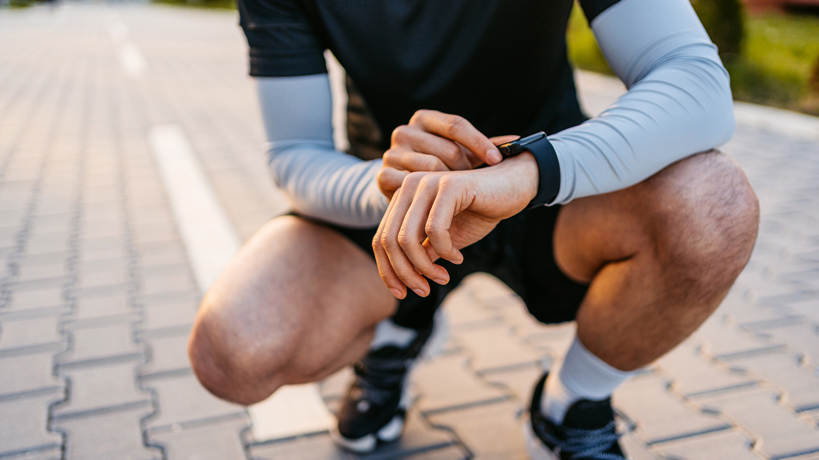 Young athlete checking fitness activity on smartwatch after working out in outdoors gym. Close-up.