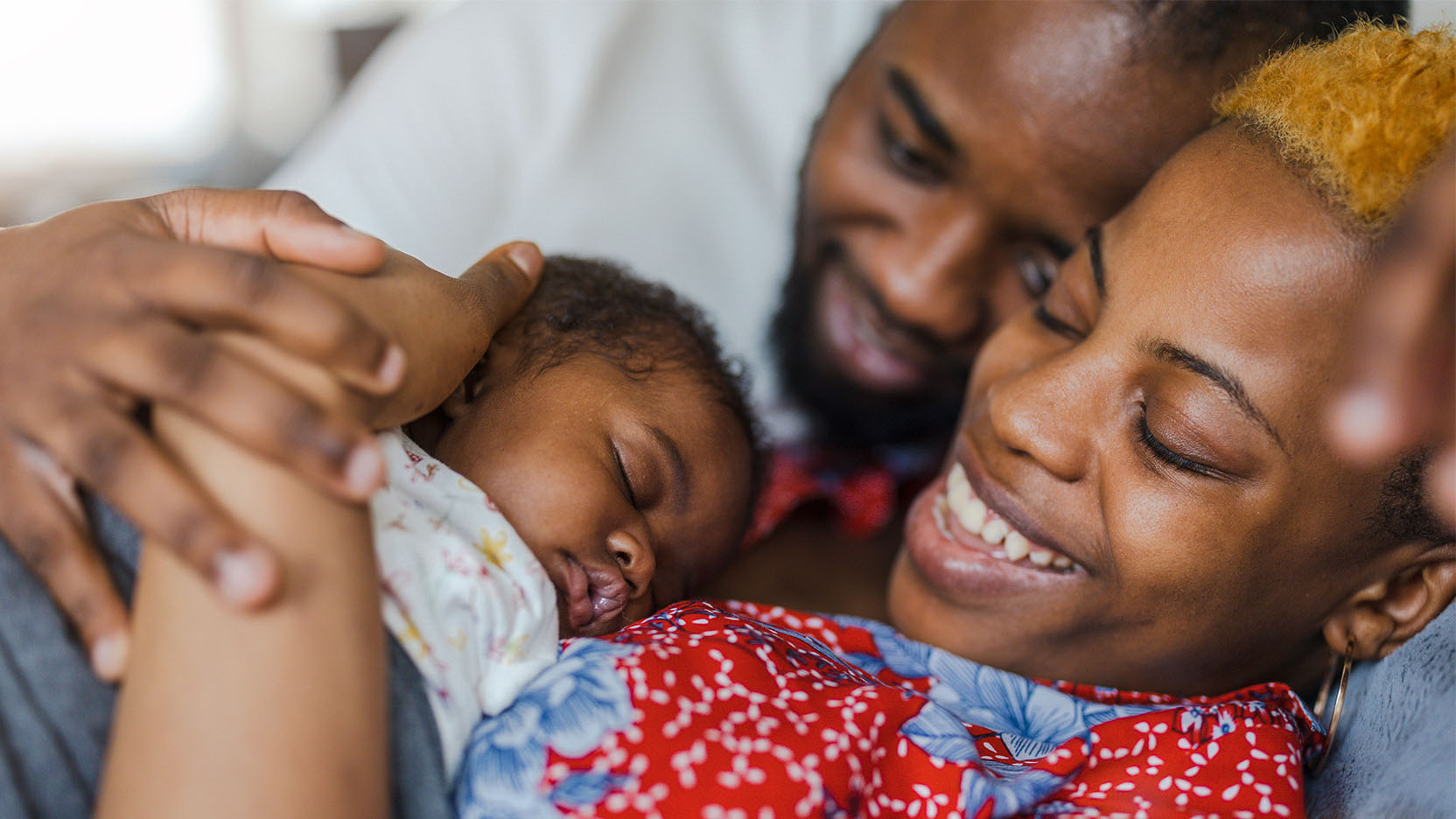 Parents admiring newborn baby on mother's chest.