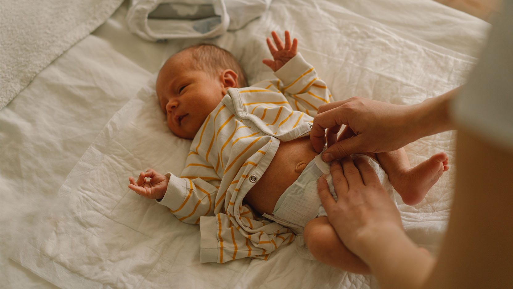 Parents changing a newborn’s diaper on a changing pad.