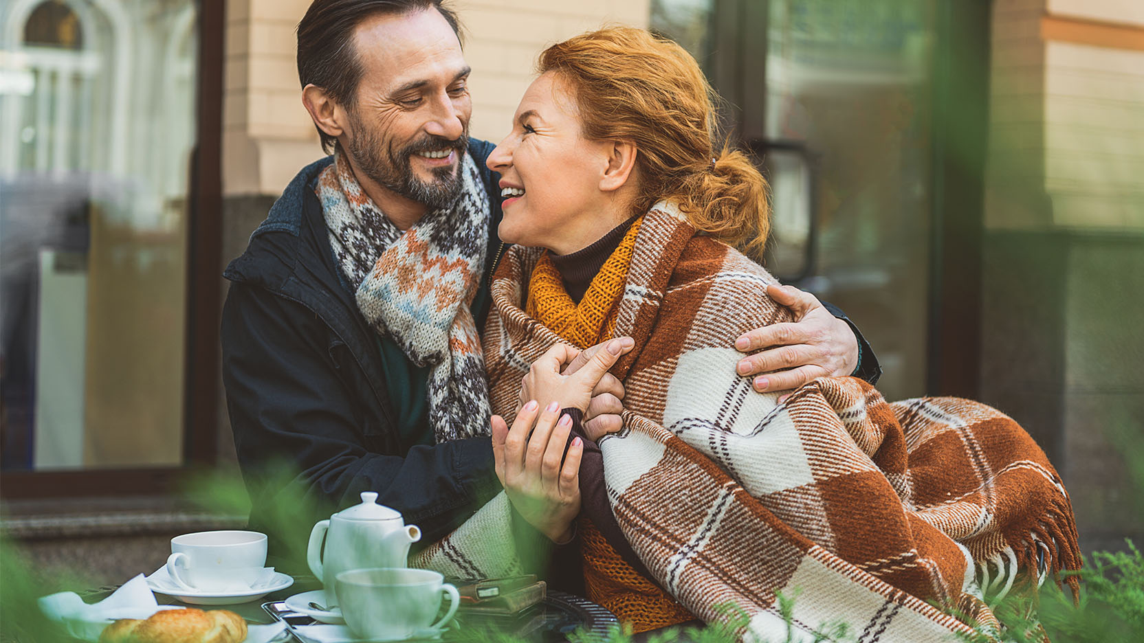 Affectionate older couple enjoys tea outside of a cafe.