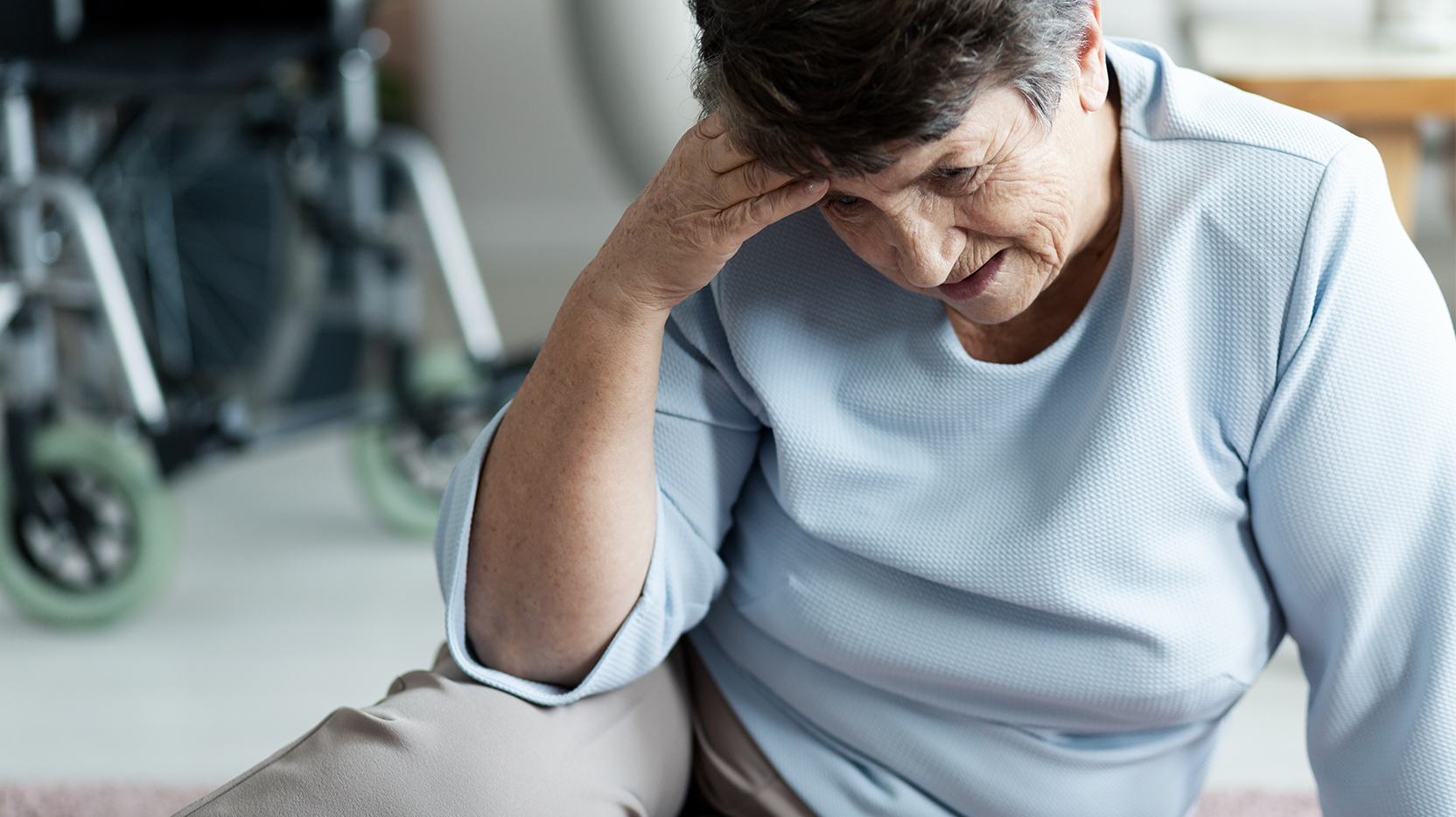 Elderly woman holds her head after a fall.