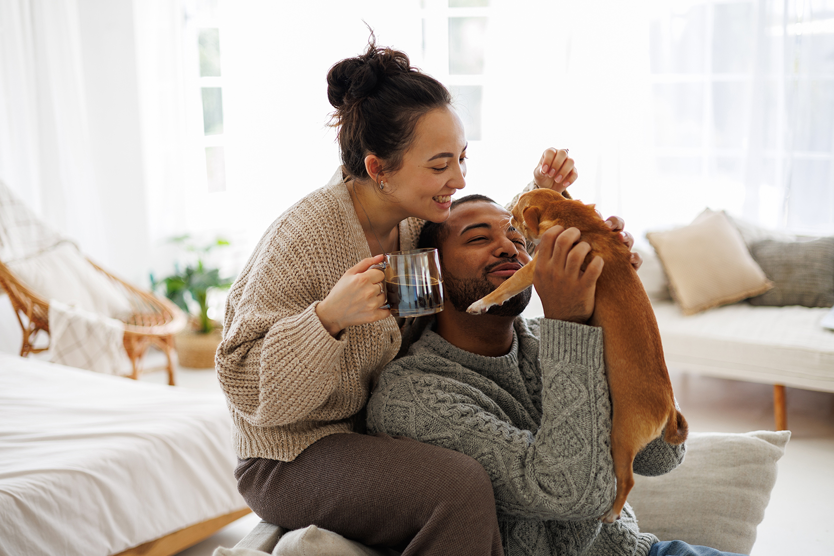 Young couple at home playing with their dog 