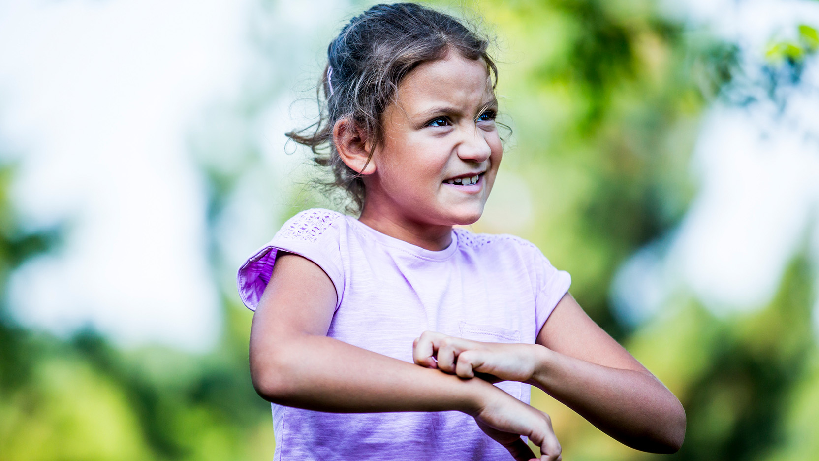 Girl scratching her hand in park.