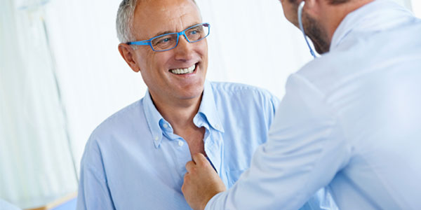 Doctor listening to heart of white male patient