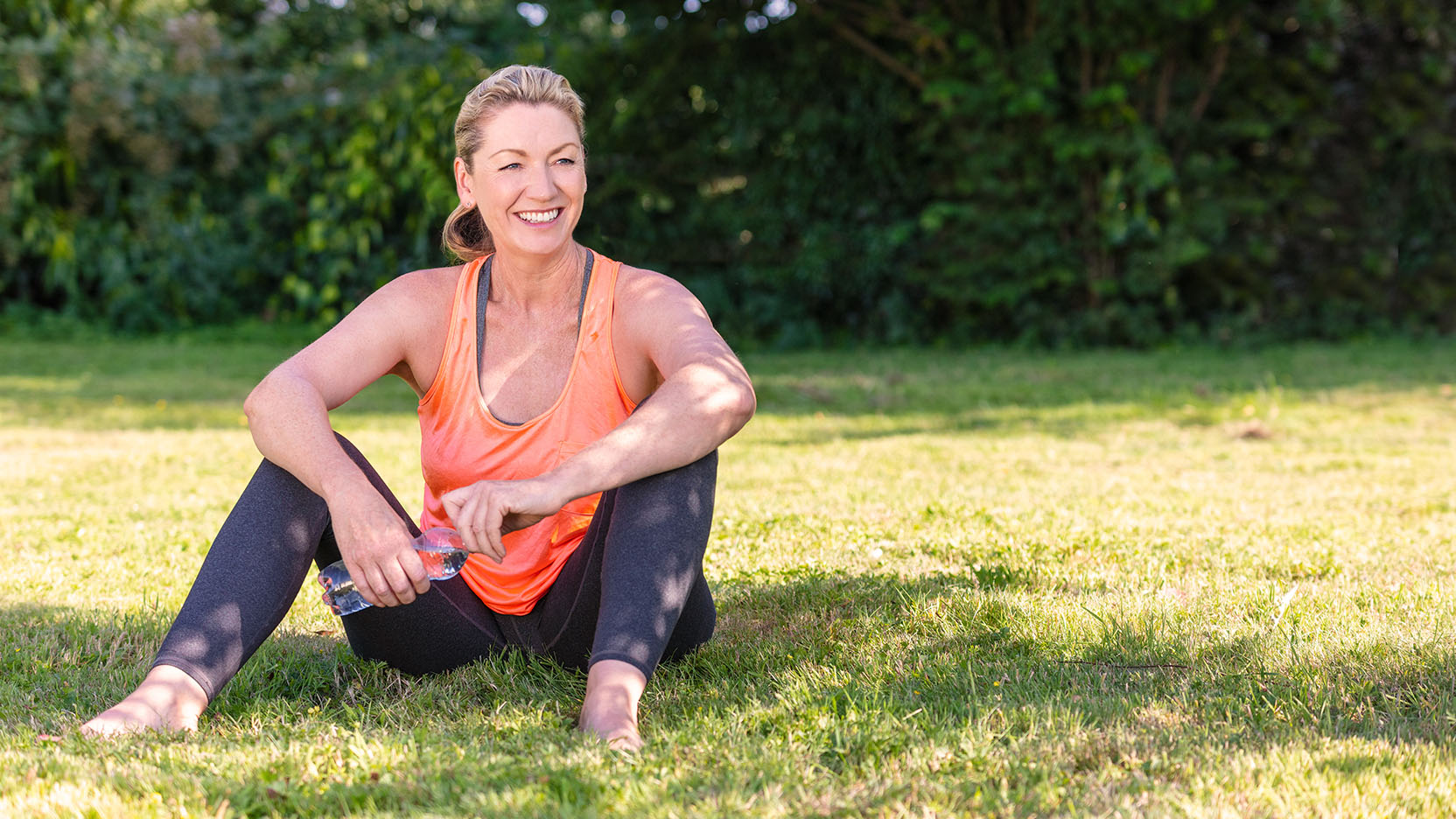 A menopausal woman seated in the grass after exercising