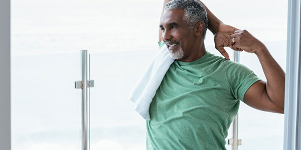 A man smiles as he stretches on a balcony