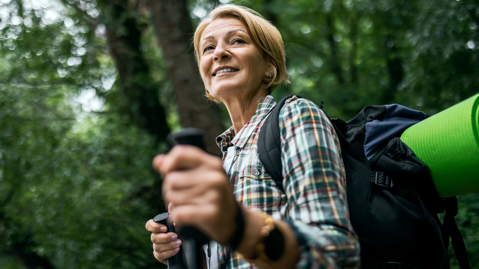 Mid adult woman in the forest hiking with hiking poles