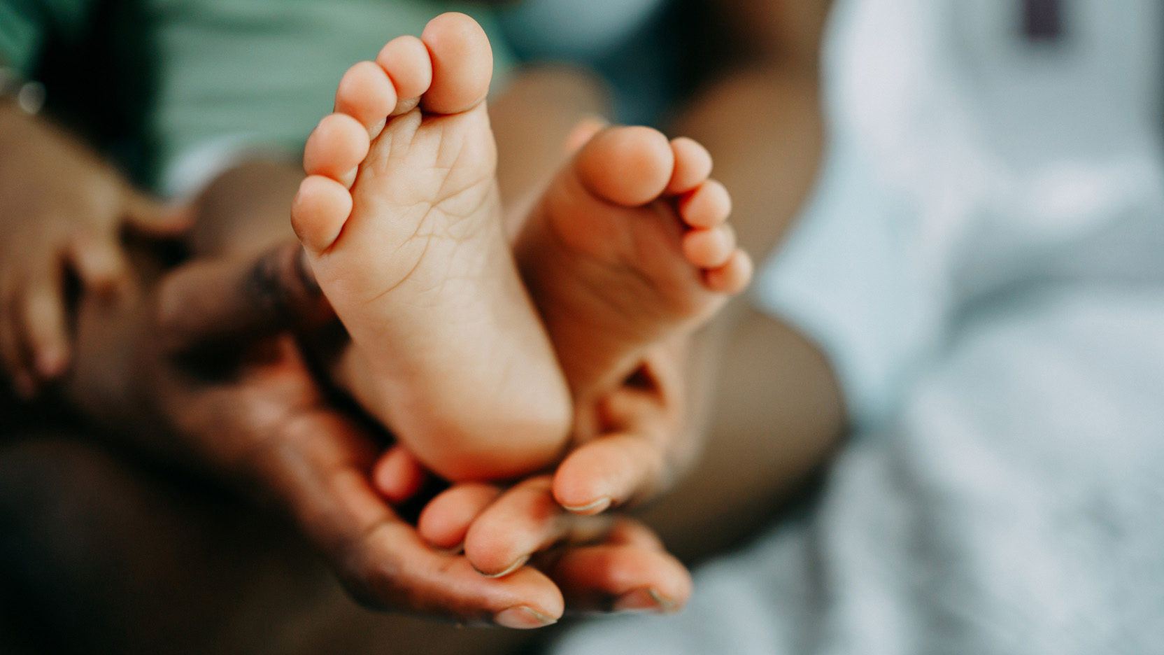 Mother's hand holds baby's leg close-up.