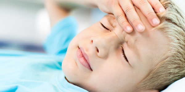 Young boy laying down holding forehead