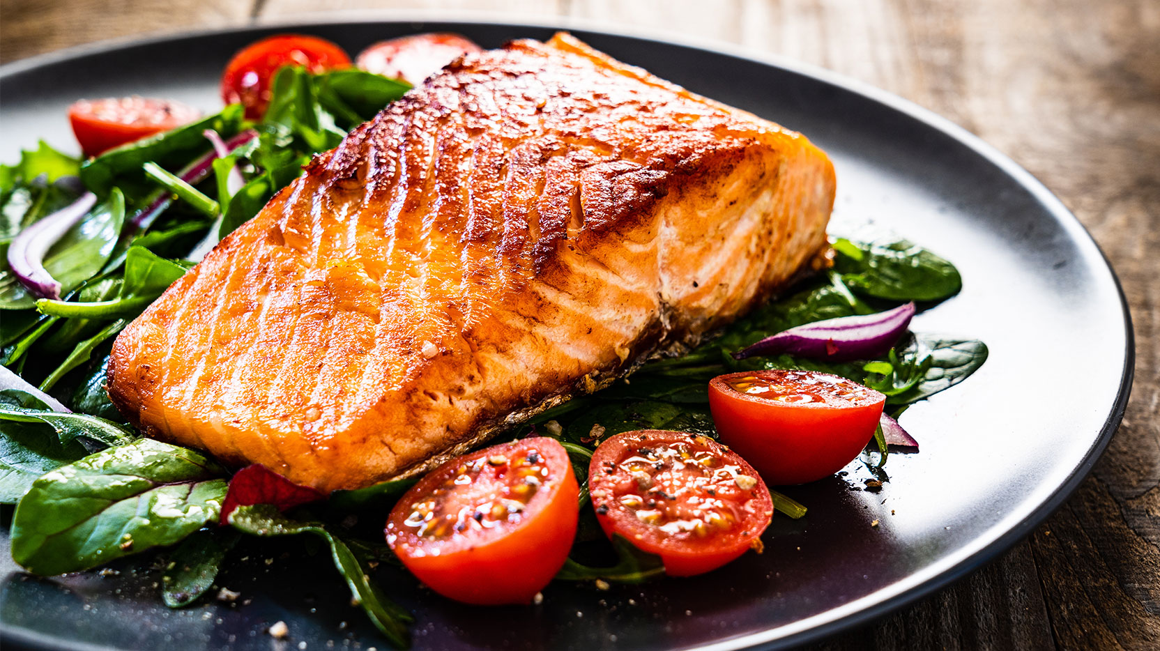 Salmon steak with vegetables on wooden table
