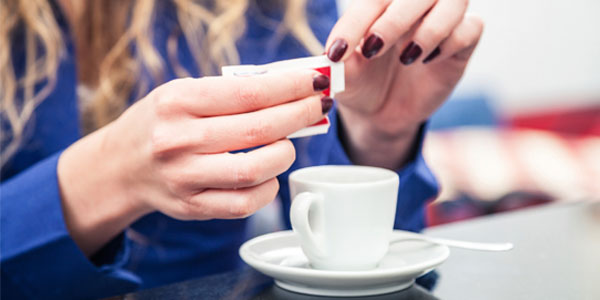 Woman opening packet of sugar for coffee