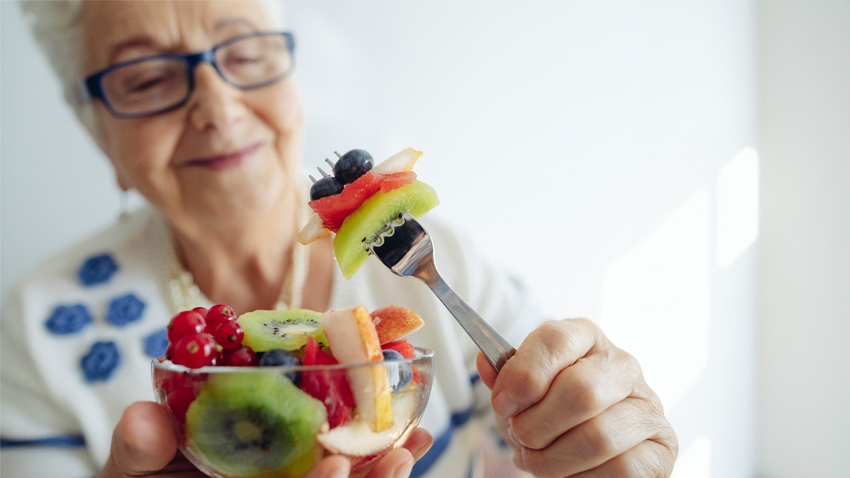 Senior woman at home eating fruit.