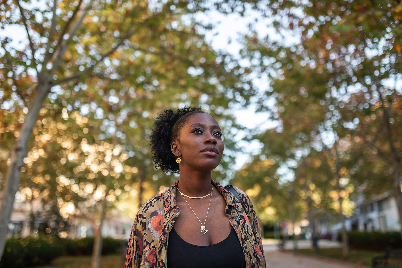 Serious young woman walking outdoors on a treelined path