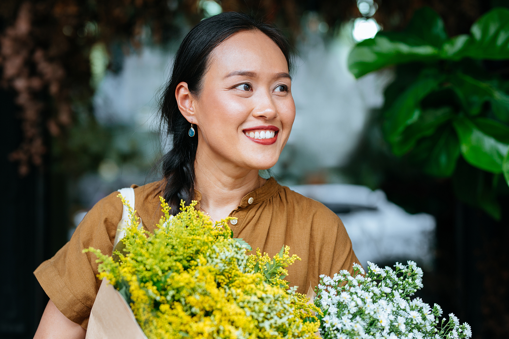 A smiling young woman holding bouquets of flowers