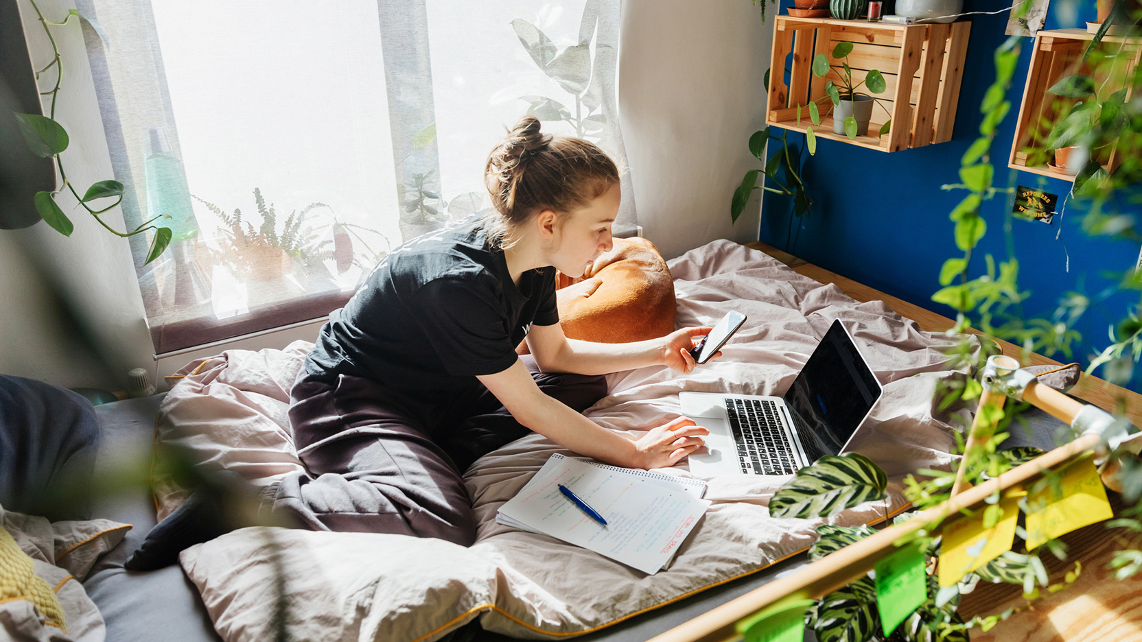 A teenage girl attending school class using zoom on her laptop and studying in her bedroom at home.