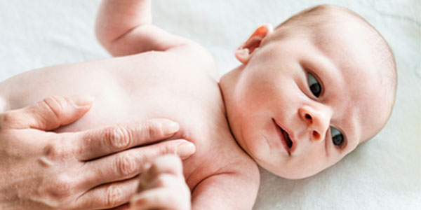Mother rubbing lotion on baby's skin