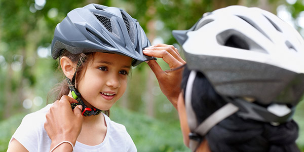 Mom adjusting little girl's helmet