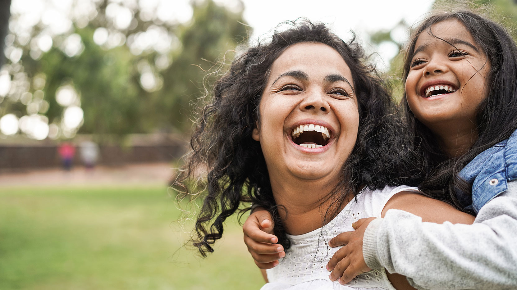 mom-with-daughter-on-back-laughing-outside