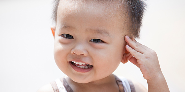 Asian toddler touching head