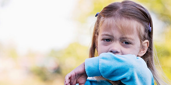 Girl coughing into her sleeve