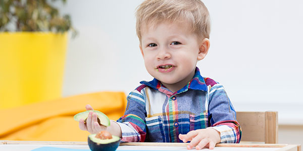 Toddler eating avocado