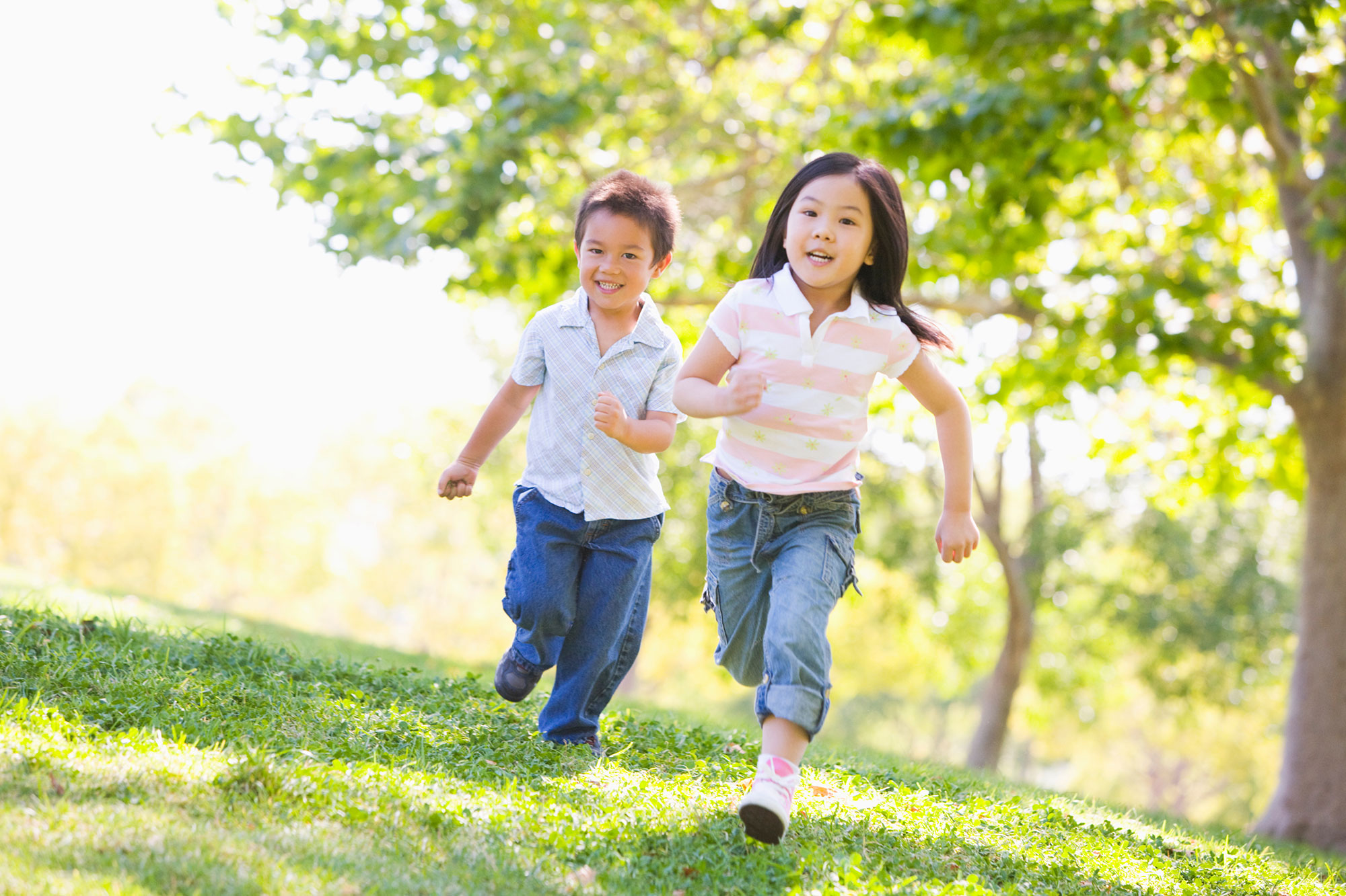 Two children running across a park 
