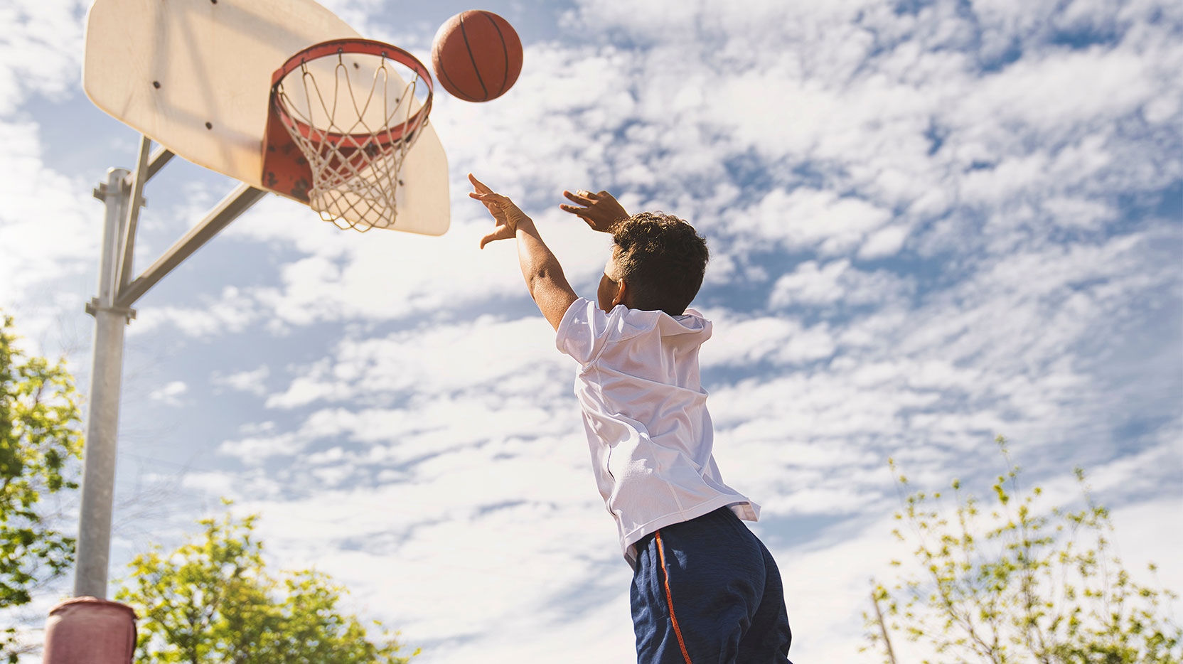 Young boy shooting basketball outside