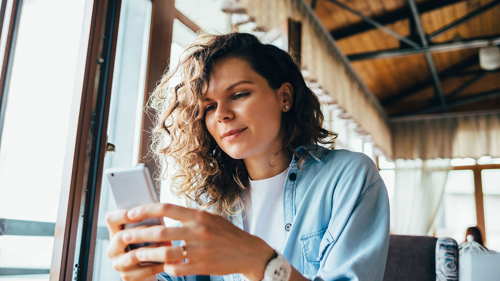 Woman at coffee shop smiling at her phone