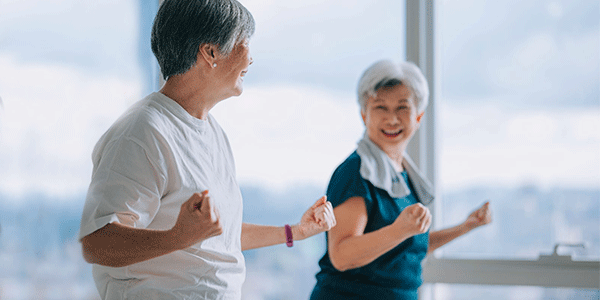 Senior woman friends enjoying home workout during evening in apartment living room
