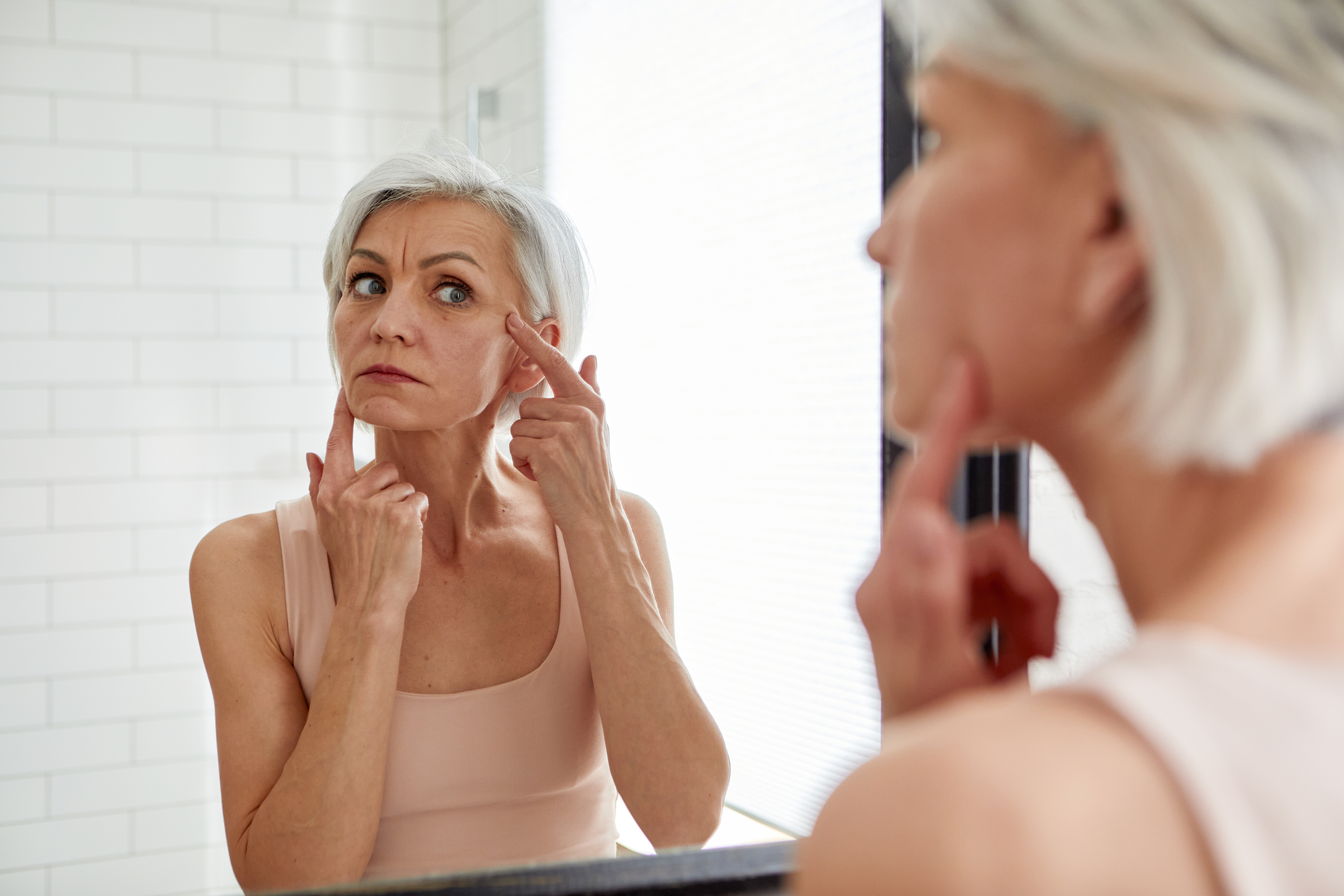 Elderly woman examining face in mirror