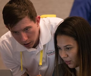 Tessitura team member looking at laptop with Tessitura users during a part Tessitura Learning and Community Conference.