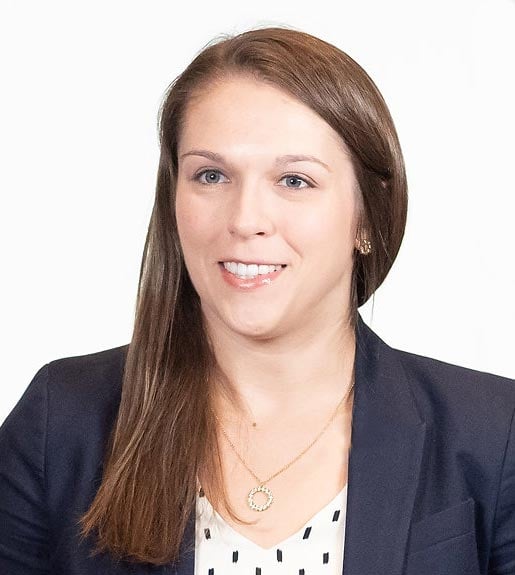 Jennifer Barton, seen from the torso up, wearing a navy blazer with her hair falling over one shoulder.