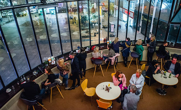 Audience members talk and enjoy concessions in the circular, glass-filled lobby of the Liverpool Playhouse Theatre