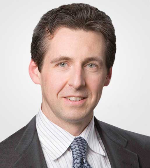 Criss Henderson, seen from the shoulders up, wearing a jacket and tie and smiling slightly.