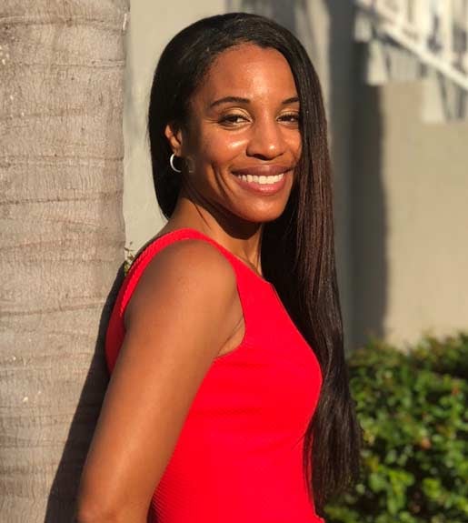 Nicole Smith, wearing a red dress. She is standing in profile and her head is turned toward the camera.