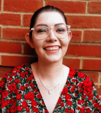 Headshot of Chloe Burton with black hair pulled back, clear glasses on, wearing a floral shirt.