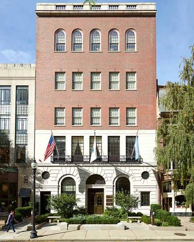 The exterior of a building under a blue sky. The upper three stories are brick; the first two stories are pale stone, with 'New England Historic Genealogical Society' carved into it.